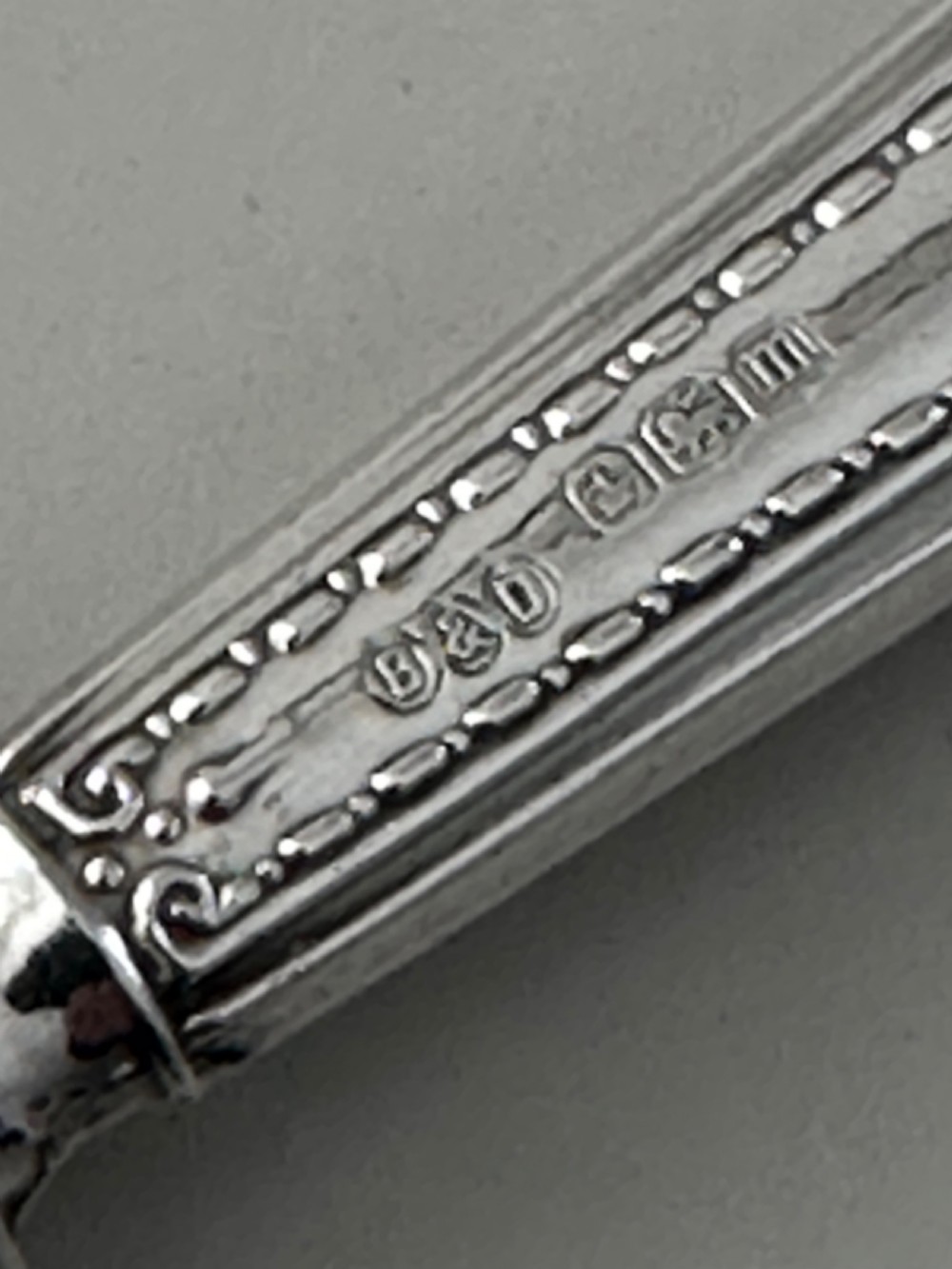 A set of six Edwardian silver butter knives with engraved handles resting inside a dark velvet-lined presentation box. View II