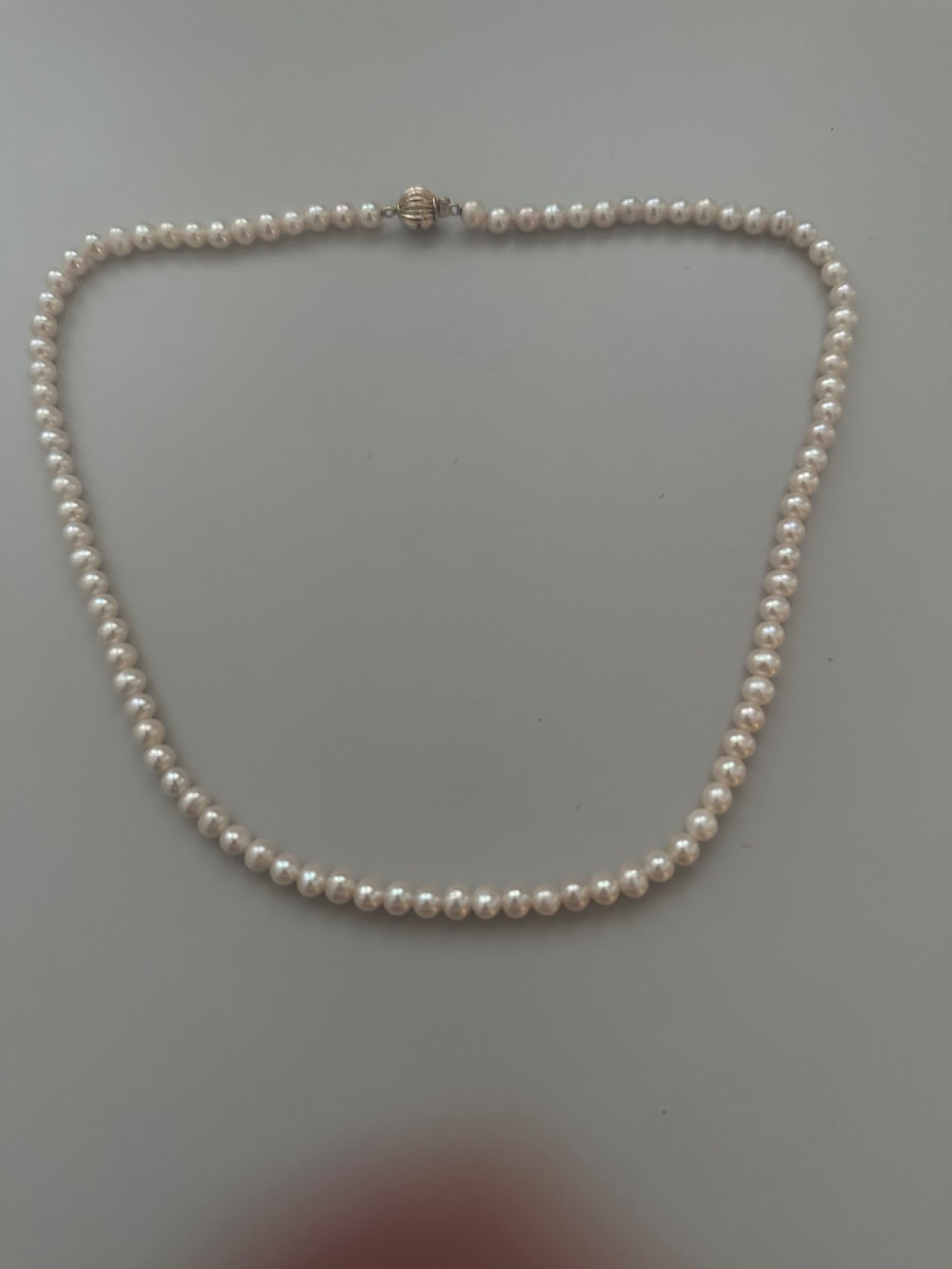 A single strand vintage cultured pearl necklace featuring uniform cream pearls and a gold shell-shaped clasp. View II
