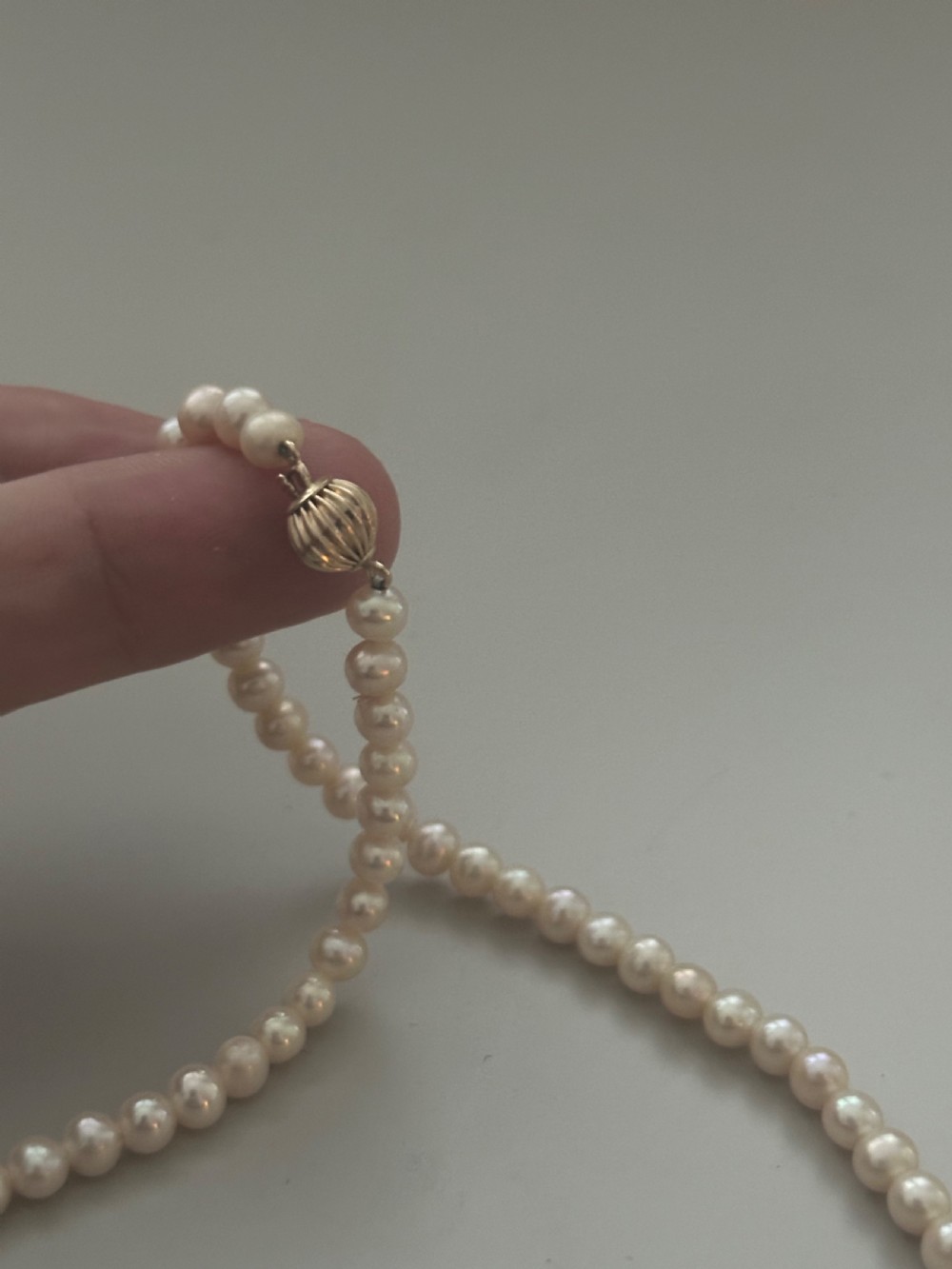 A single strand vintage cultured pearl necklace featuring uniform cream pearls and a gold shell-shaped clasp. View III