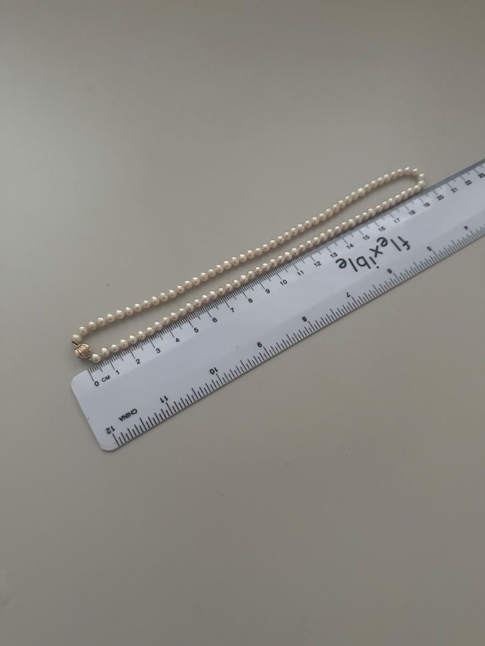 A single strand vintage cultured pearl necklace featuring uniform cream pearls and a gold shell-shaped clasp. View IV
