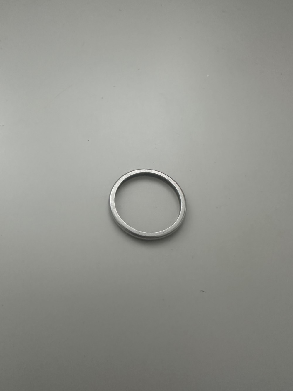 A plain platinum wedding band displayed inside an open vintage velvet-lined leather ring box. View IV