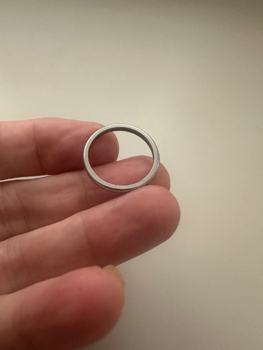 A plain platinum wedding band displayed inside an open vintage velvet-lined leather ring box. View V