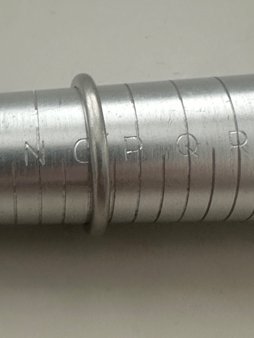 A plain platinum wedding band displayed inside an open vintage velvet-lined leather ring box. View VII