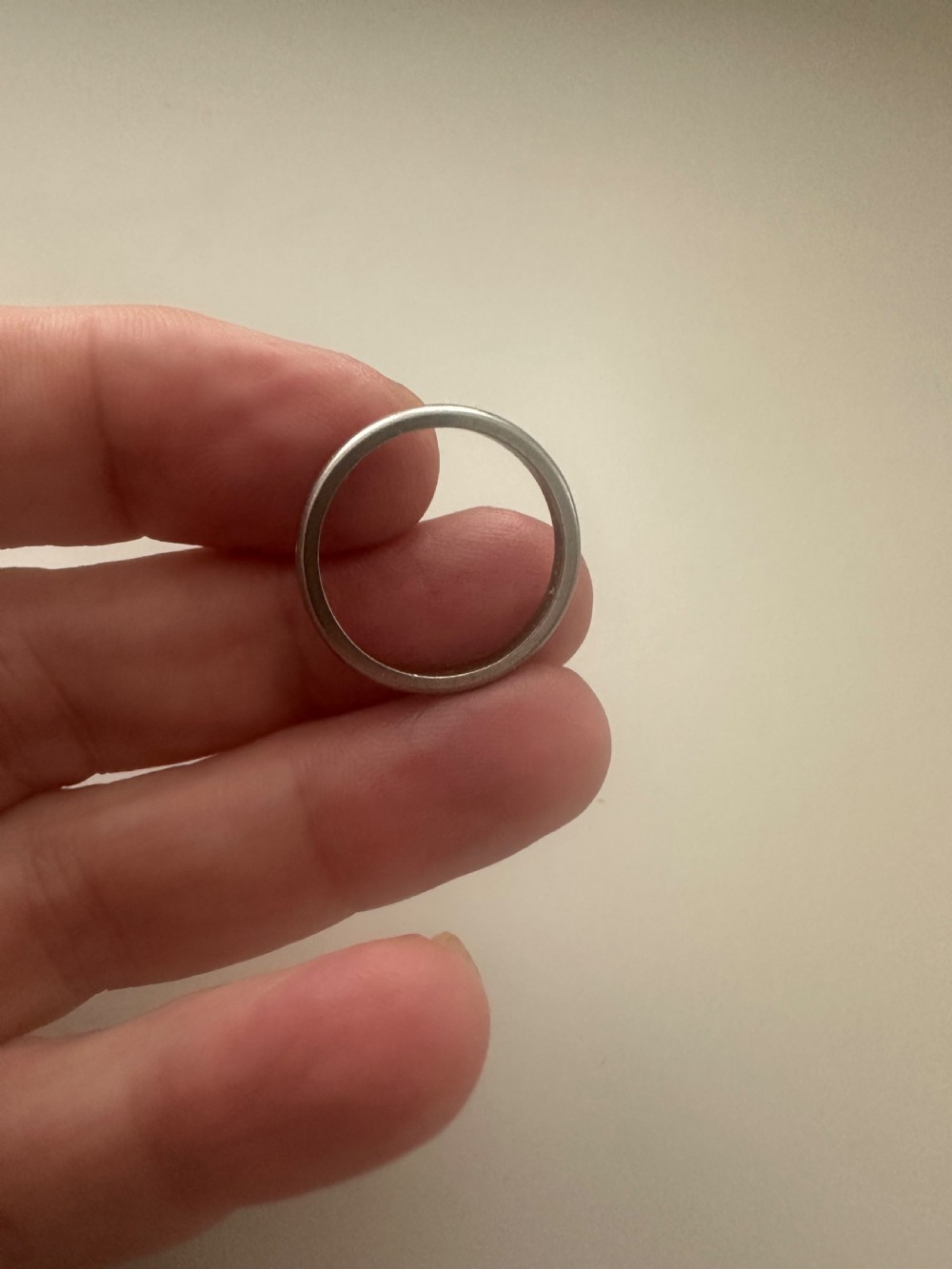 A plain platinum wedding band displayed inside an open vintage velvet-lined leather ring box. View VIII