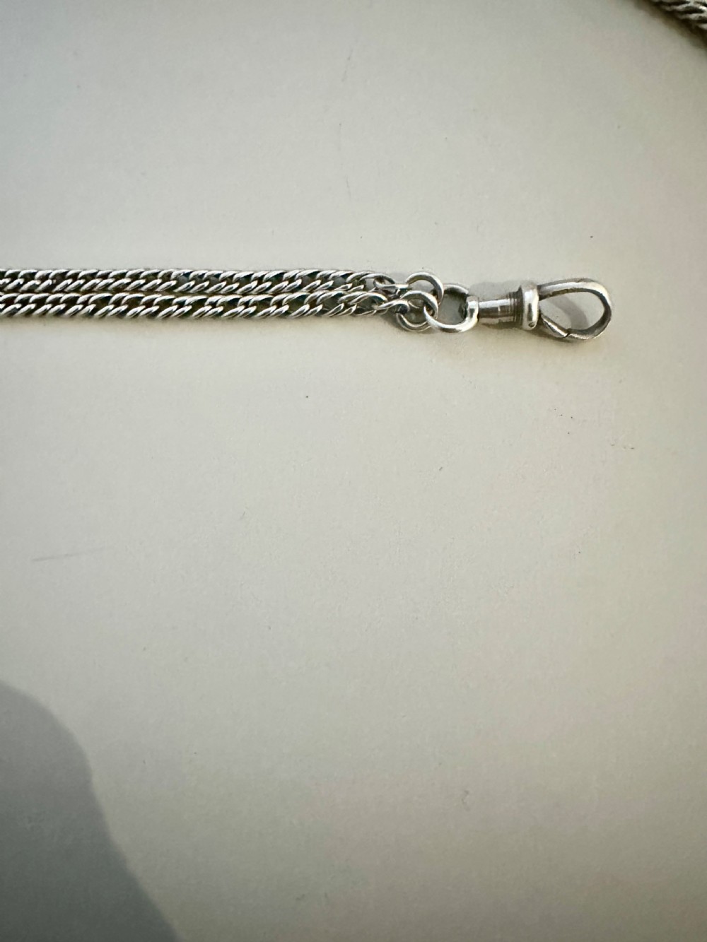A long, finely linked Victorian sterling silver guard chain featuring an attached swivel clasp, shown coiled on a flat surface. View IV