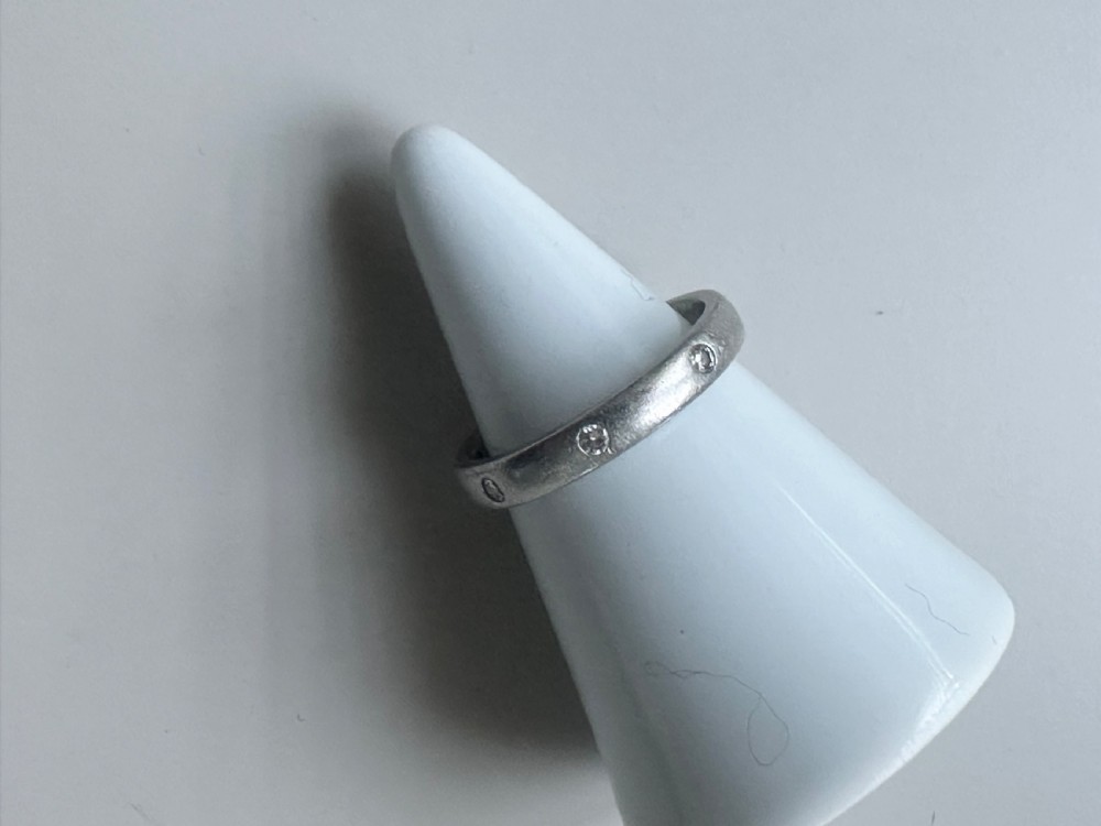 A platinum ring band inset with round diamonds sitting inside a fitted velvet presentation box. View II