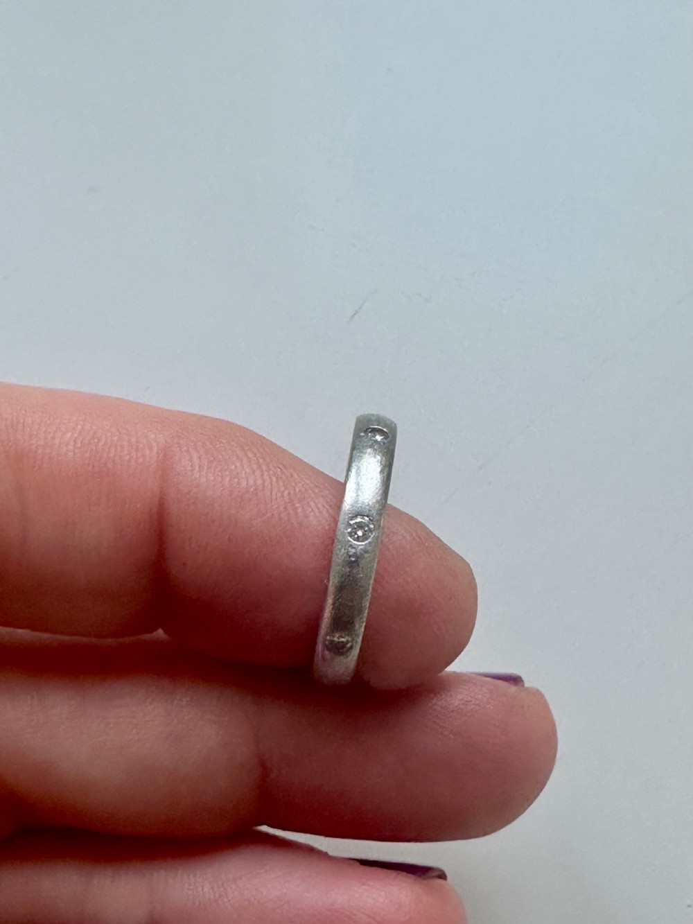 A platinum ring band inset with round diamonds sitting inside a fitted velvet presentation box. View III