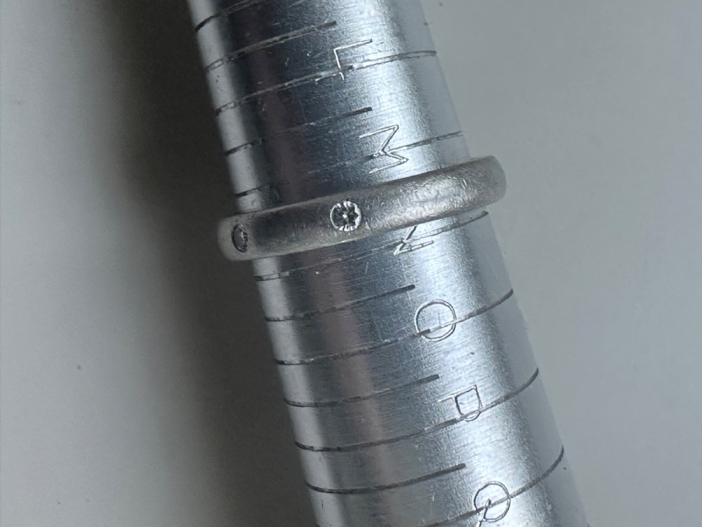 A platinum ring band inset with round diamonds sitting inside a fitted velvet presentation box. View V