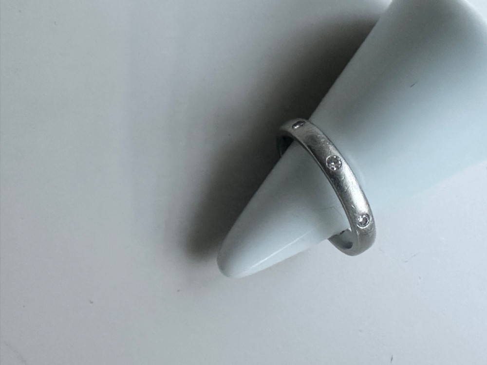 A platinum ring band inset with round diamonds sitting inside a fitted velvet presentation box. View VII