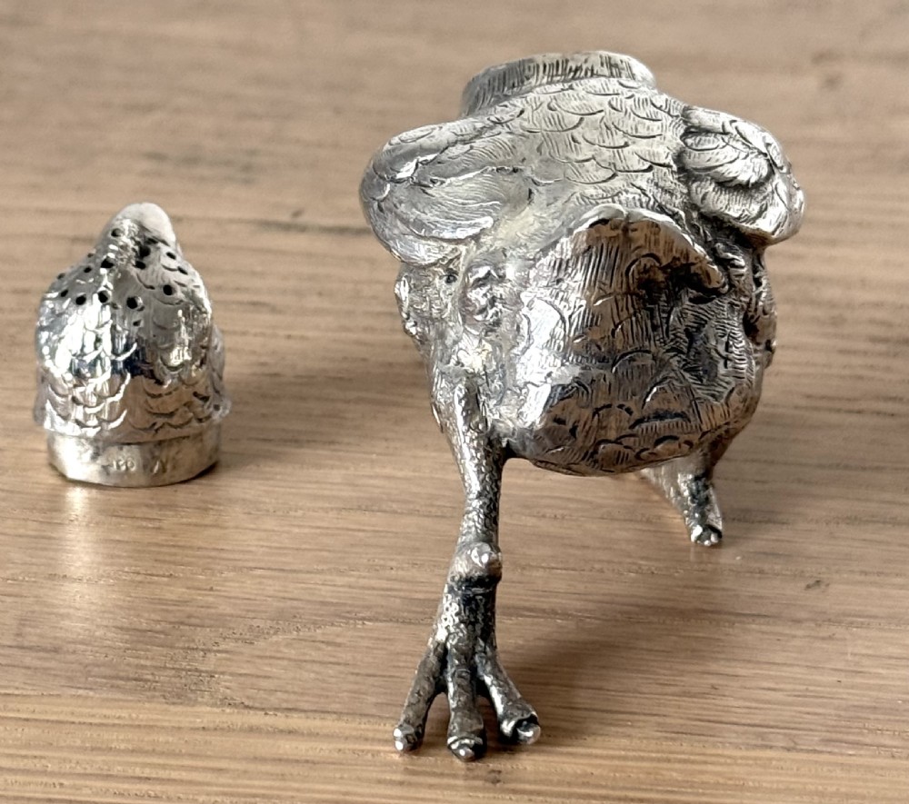 A cast silver pepper pot sculpted in the realistic shape of a chick with detailed feather engraving and a pierced head. View IV