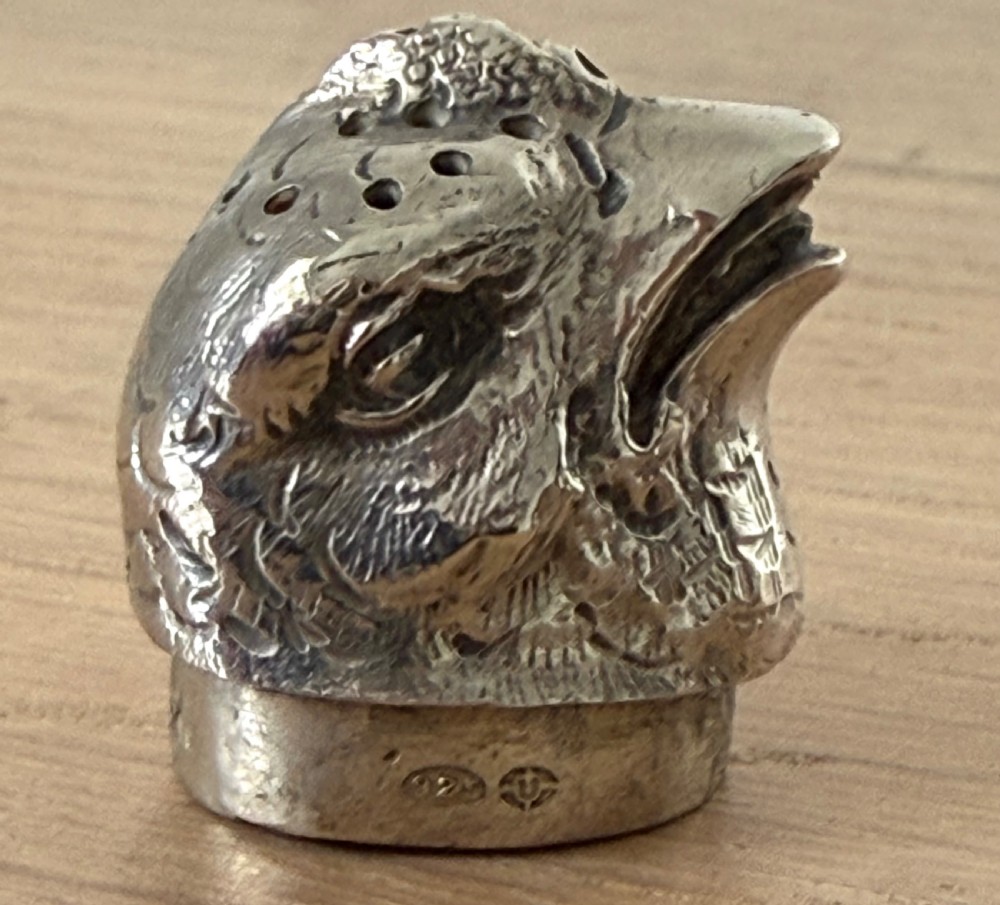 A cast silver pepper pot sculpted in the realistic shape of a chick with detailed feather engraving and a pierced head. View V