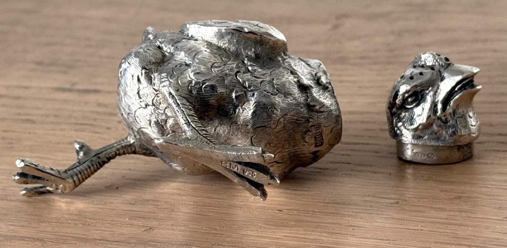 A cast silver pepper pot sculpted in the realistic shape of a chick with detailed feather engraving and a pierced head. View VI