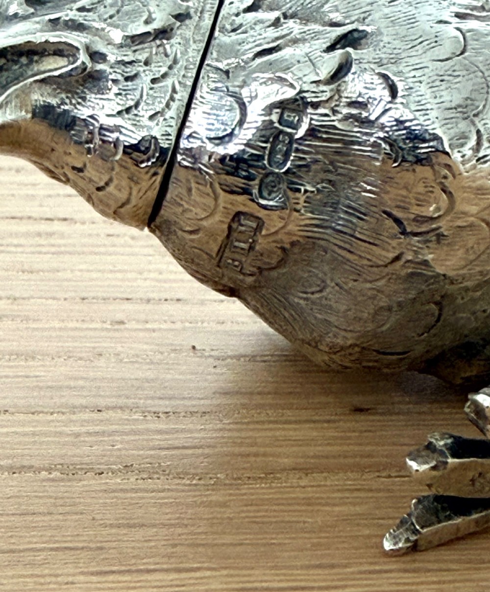 A cast silver pepper pot sculpted in the realistic shape of a chick with detailed feather engraving and a pierced head. View VIII