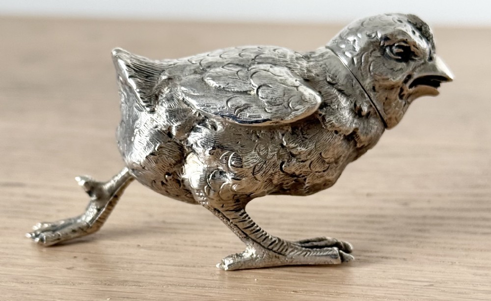 A cast silver pepper pot sculpted in the realistic shape of a chick with detailed feather engraving and a pierced head. View XII