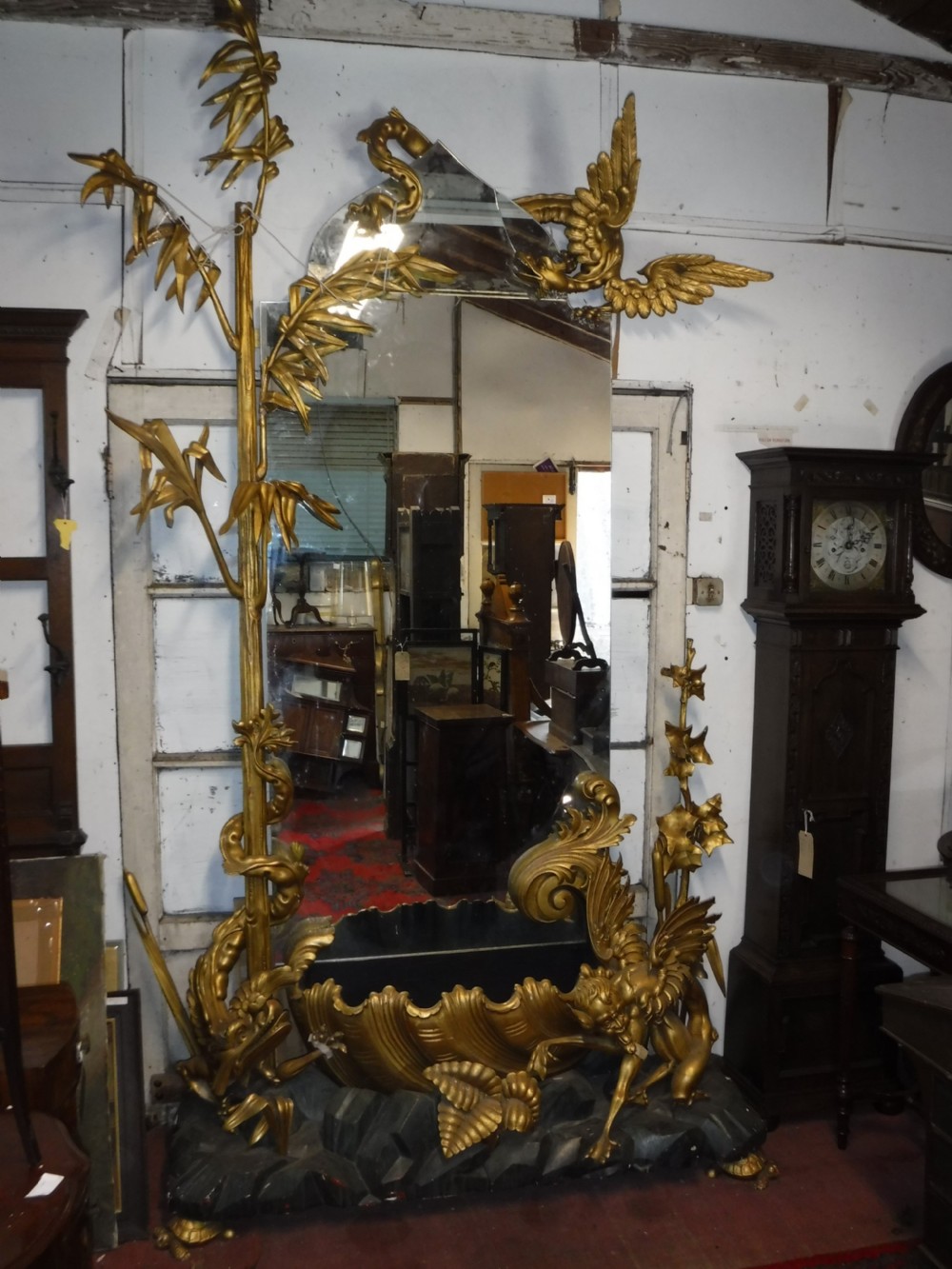A tall giltwood hall mirror adorned with carved bamboo side pillars, mythical winged dragon motifs, and a carved shell base.