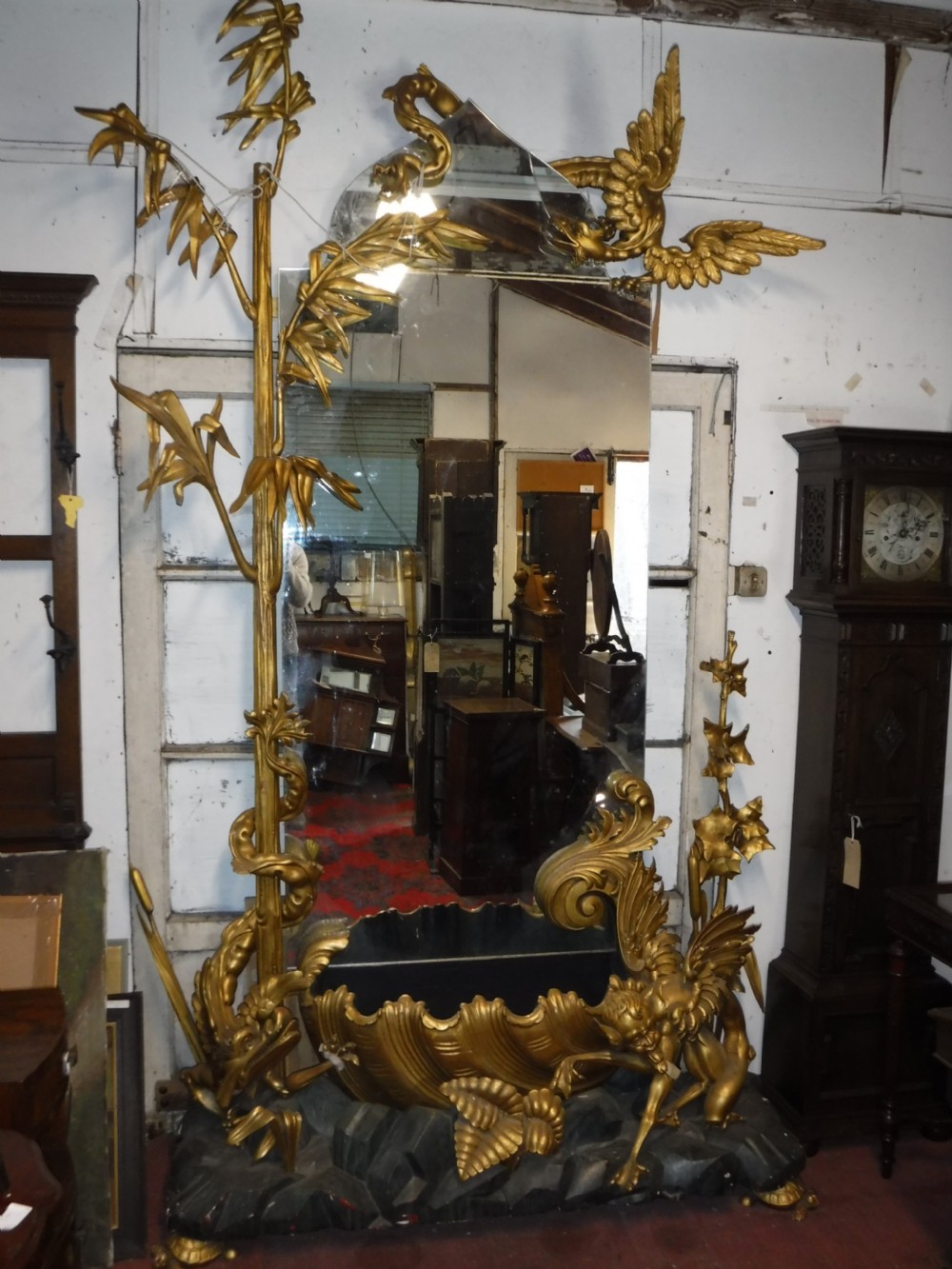 A tall giltwood hall mirror adorned with carved bamboo side pillars, mythical winged dragon motifs, and a carved shell base. View II