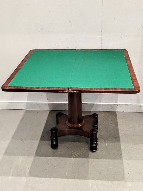 fig 1. A Georgian mahogany card table featuring a hinged fold-over top, carved acanthus apron brackets, a turned pedestal column, and a shaped plinth base on turned feet.