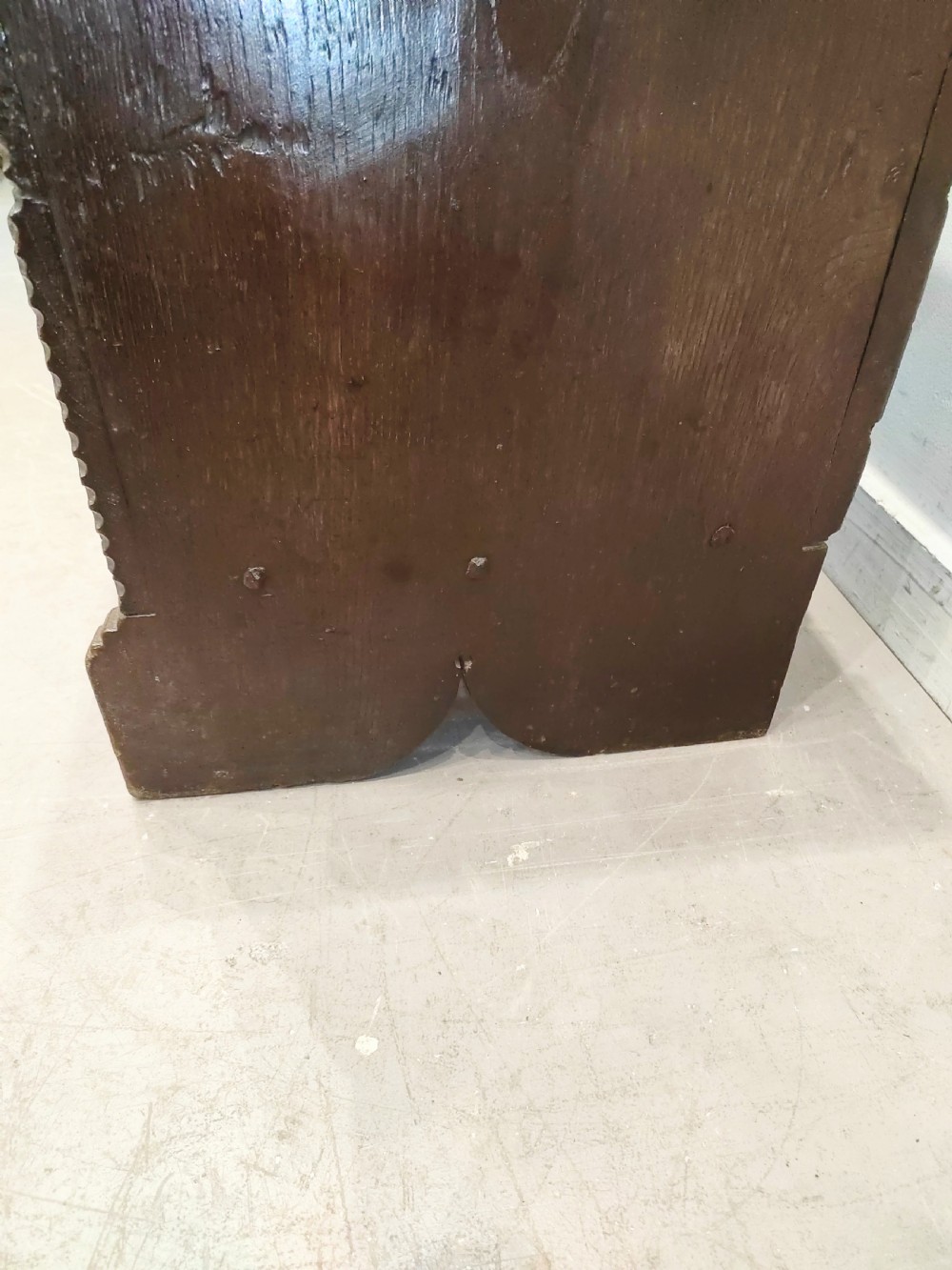 A dark brown 17th-century carved oak coffer with a flat lid, carved roundel frieze, arcaded lower section, and V-cut slab end legs. View V