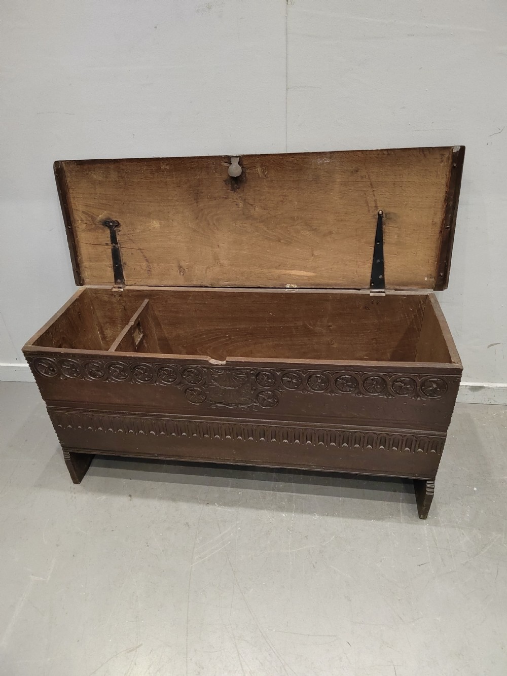 A dark brown 17th-century carved oak coffer with a flat lid, carved roundel frieze, arcaded lower section, and V-cut slab end legs. View VI
