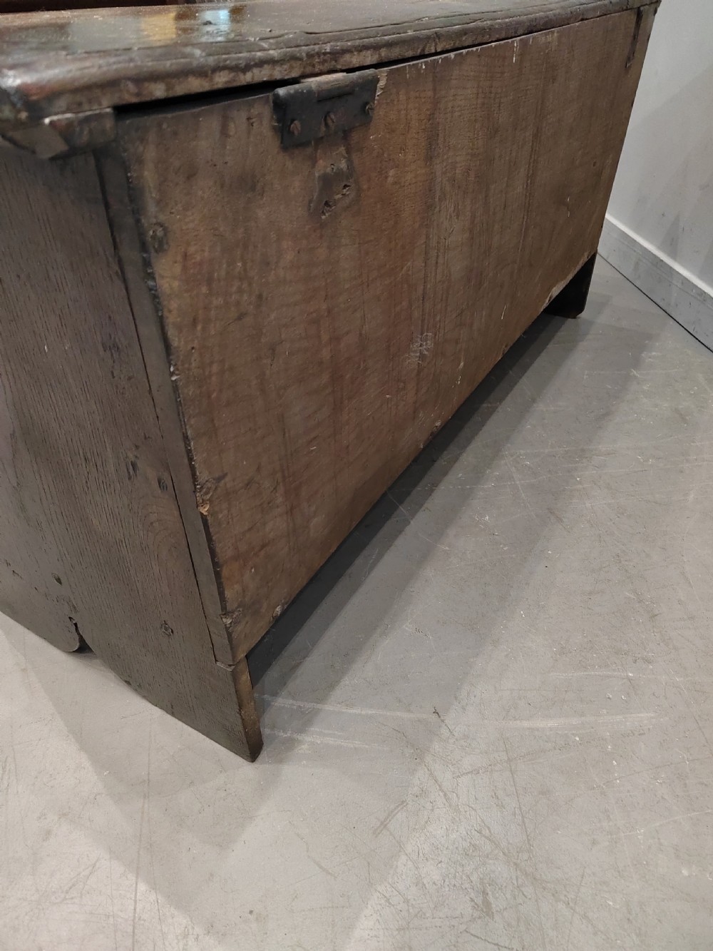 A dark brown 17th-century carved oak coffer with a flat lid, carved roundel frieze, arcaded lower section, and V-cut slab end legs. View VII