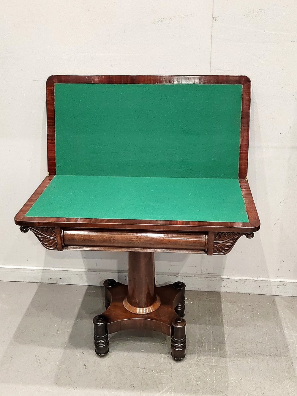 A Georgian mahogany card table featuring a hinged fold-over top, carved acanthus apron brackets, a turned pedestal column, and a shaped plinth base on turned feet. View III