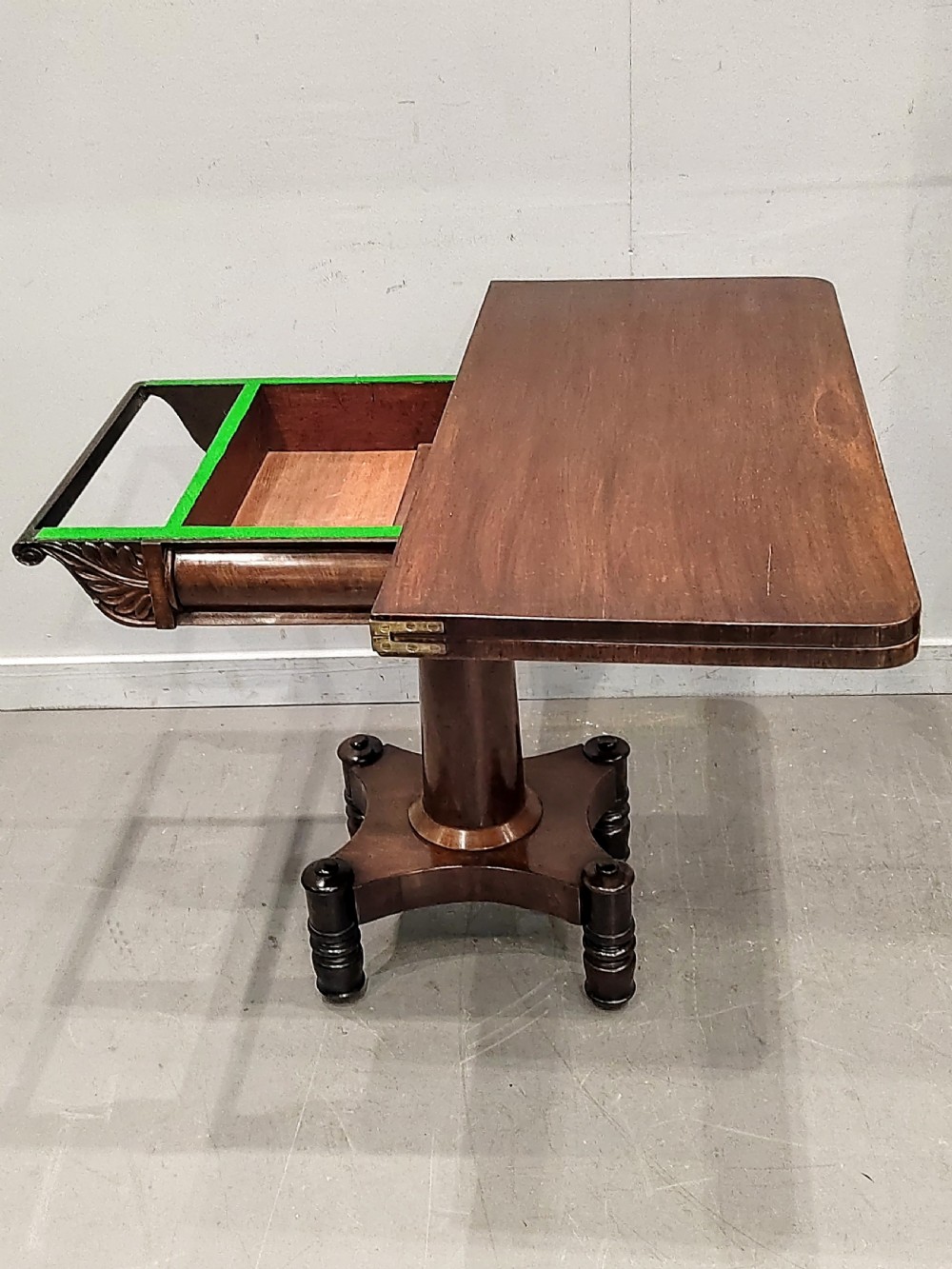 A Georgian mahogany card table featuring a hinged fold-over top, carved acanthus apron brackets, a turned pedestal column, and a shaped plinth base on turned feet. View IV