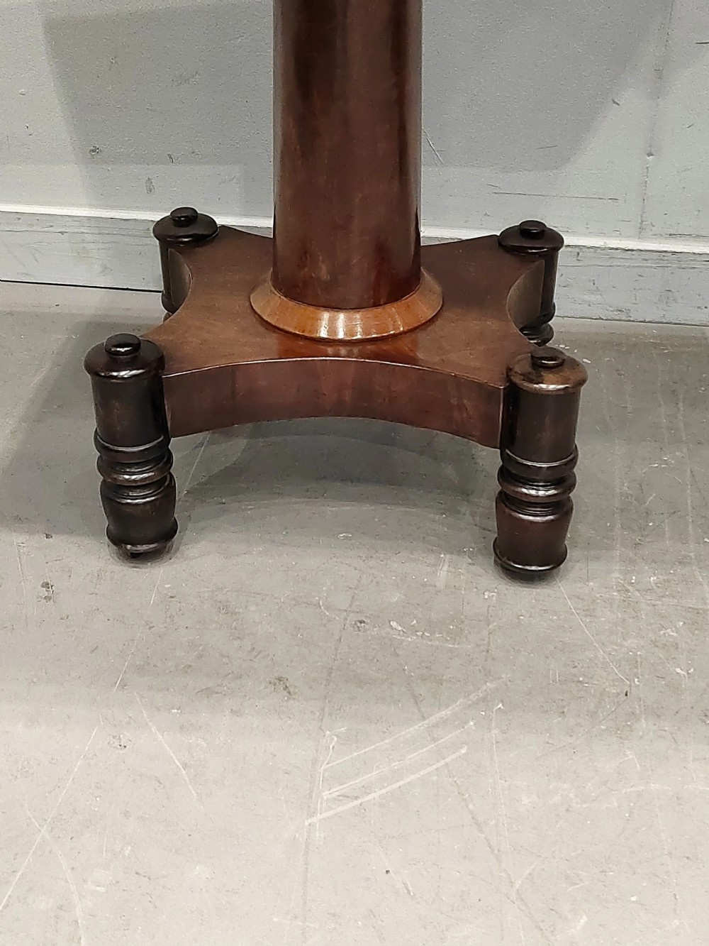 A Georgian mahogany card table featuring a hinged fold-over top, carved acanthus apron brackets, a turned pedestal column, and a shaped plinth base on turned feet. View VI