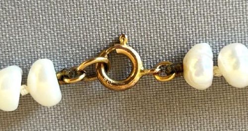 fig 1. A 9ct gold strand necklace composed of irregular off-white freshwater pearls interspersed with small spherical brown tigers eye beads.