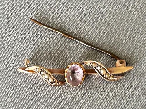 An Edwardian 9ct yellow gold bar brooch featuring a central claw-set oval amethyst flanked by S-scroll shoulders set with tiny seed pearls. View III