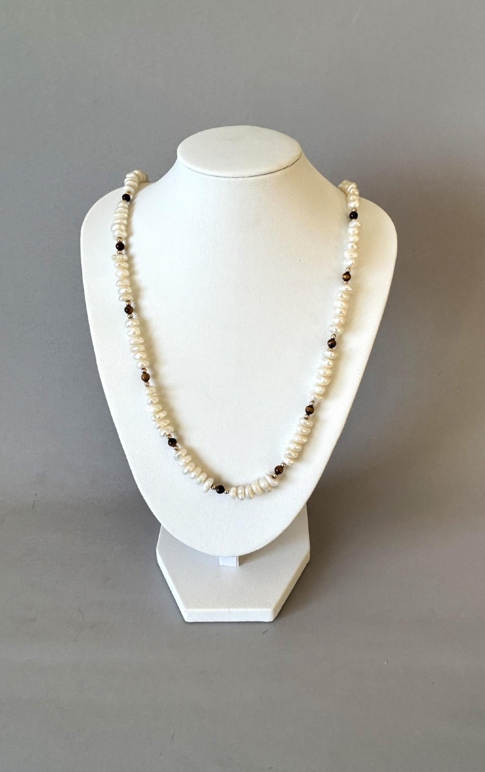A 9ct gold strand necklace composed of irregular off-white freshwater pearls interspersed with small spherical brown tigers eye beads. View III