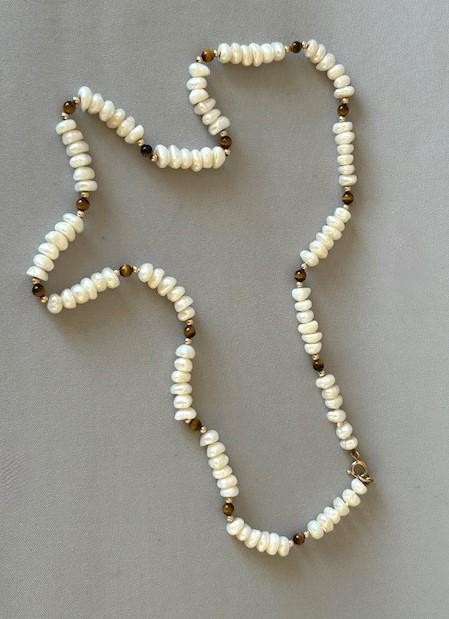 A 9ct gold strand necklace composed of irregular off-white freshwater pearls interspersed with small spherical brown tigers eye beads. View V
