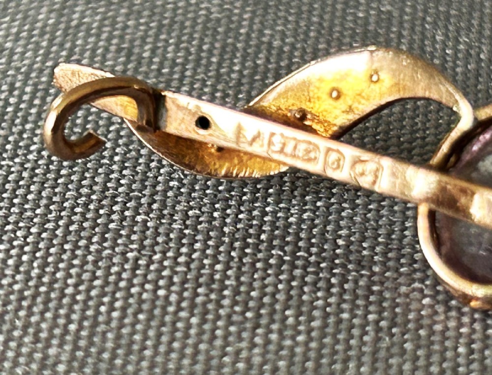 An Edwardian 9ct yellow gold bar brooch featuring a central claw-set oval amethyst flanked by S-scroll shoulders set with tiny seed pearls. View IV