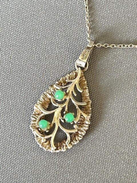 A teardrop-shaped silver pendant featuring textured edges, openwork branch motifs, and three small green chrysoprase cabochons suspended on a fine silver chain. View V