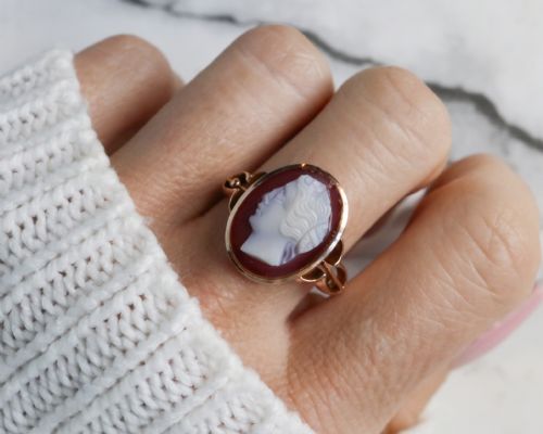 fig 1. An antique nine-carat gold ring featuring an oval relief carving of a classical female profile set against a red background.