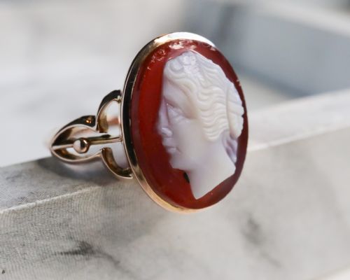 fig 4. An antique nine-carat gold ring featuring an oval relief carving of a classical female profile set against a red background.