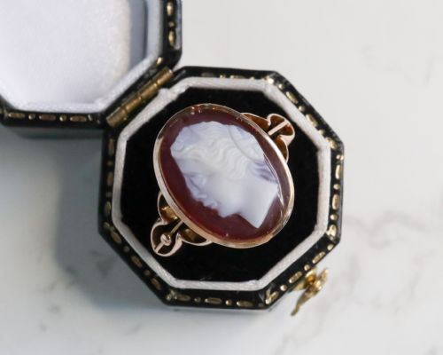 fig 5. An antique nine-carat gold ring featuring an oval relief carving of a classical female profile set against a red background.