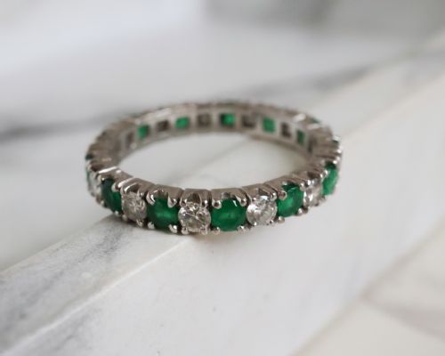 fig 2. An antique platinum full eternity ring set with alternating round green emeralds and white diamonds in a claw setting.
