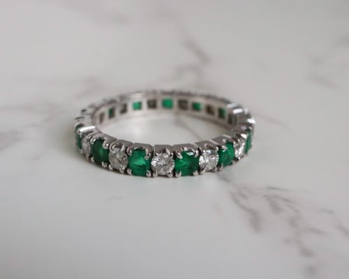 fig 3. An antique platinum full eternity ring set with alternating round green emeralds and white diamonds in a claw setting.