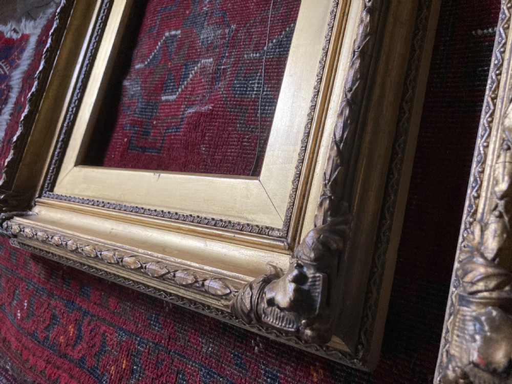 A matching pair of rectangular antique gilt gesso picture frames featuring ornate corner carvings and leaf motif mouldings. View IX