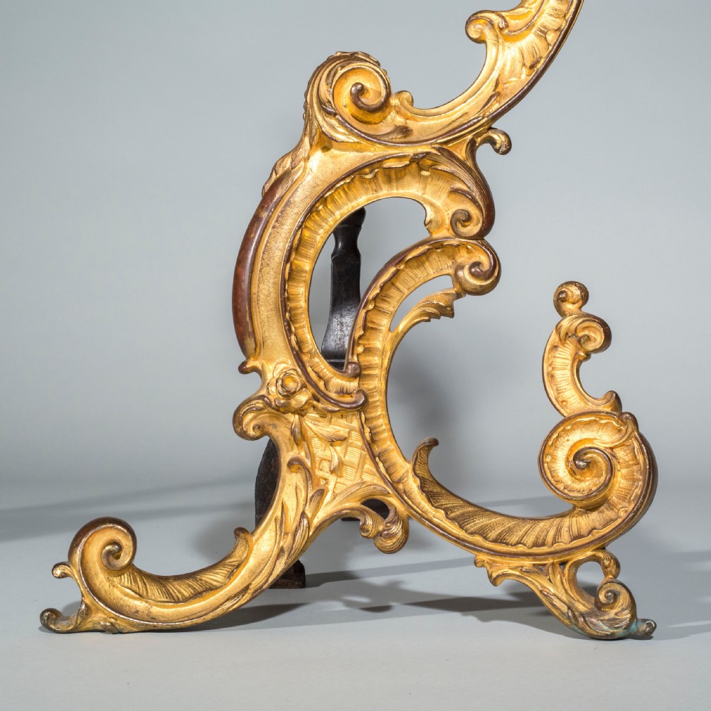A pair of 18th-century gilt bronze Rococo andirons featuring swept C-scrolls, acanthus leaf carving, and iron rear billet bars. View VI