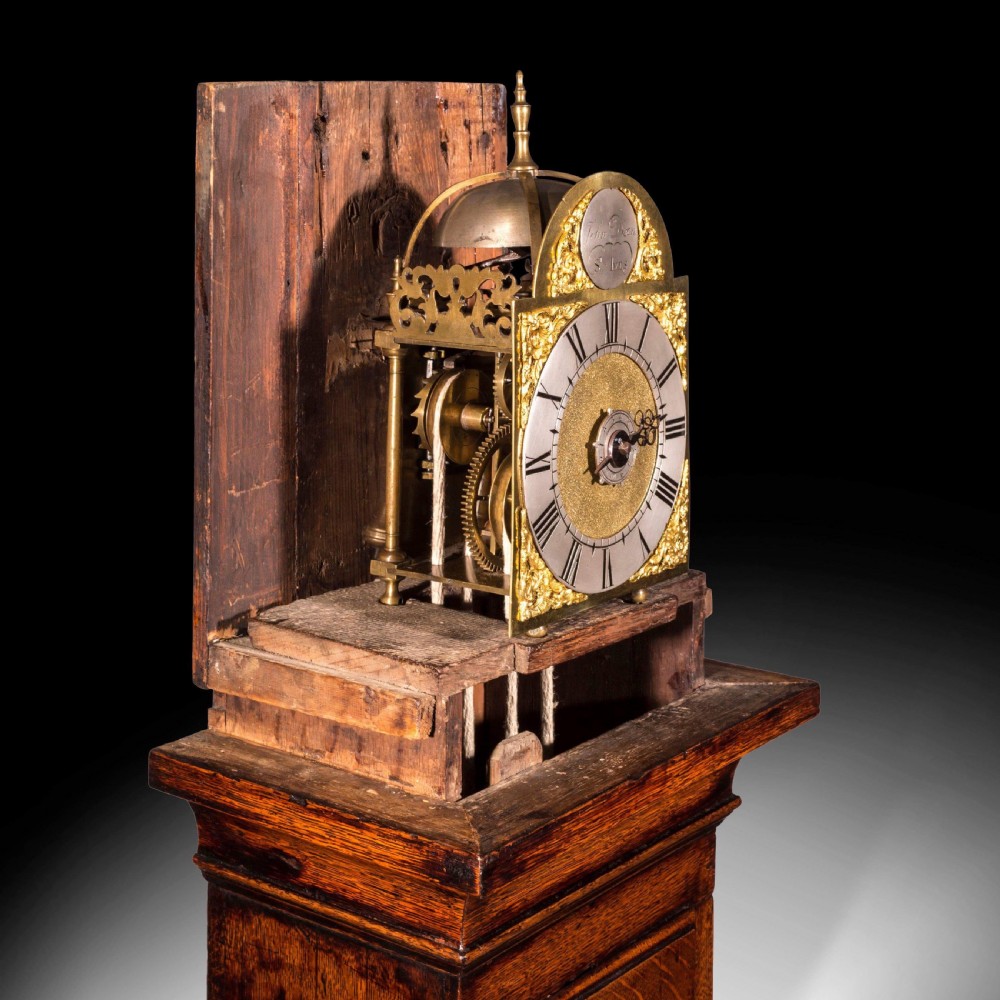 A tall Georgian longcase clock crafted from rich brown oak, featuring a brass dial, arched hood, and three brass ball finials. View II