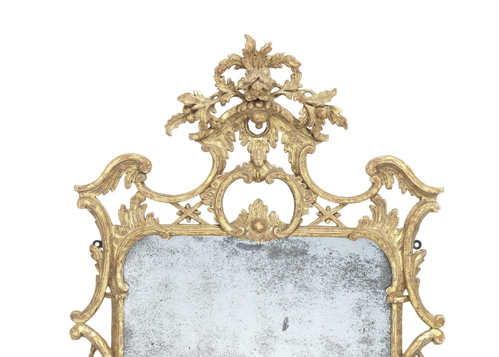 An ornate George III Rococo giltwood wall mirror featuring carved acanthus leaf cresting, scrolling borders, and a foxed mirror plate. View II
