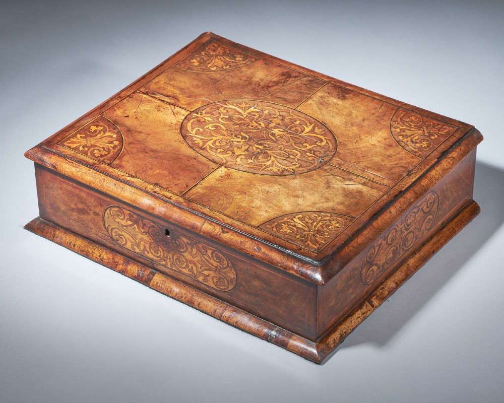 A rectangular seventeenth-century figured walnut box featuring intricate seaweed marquetry in an oval central cartouche and matching corner panels.