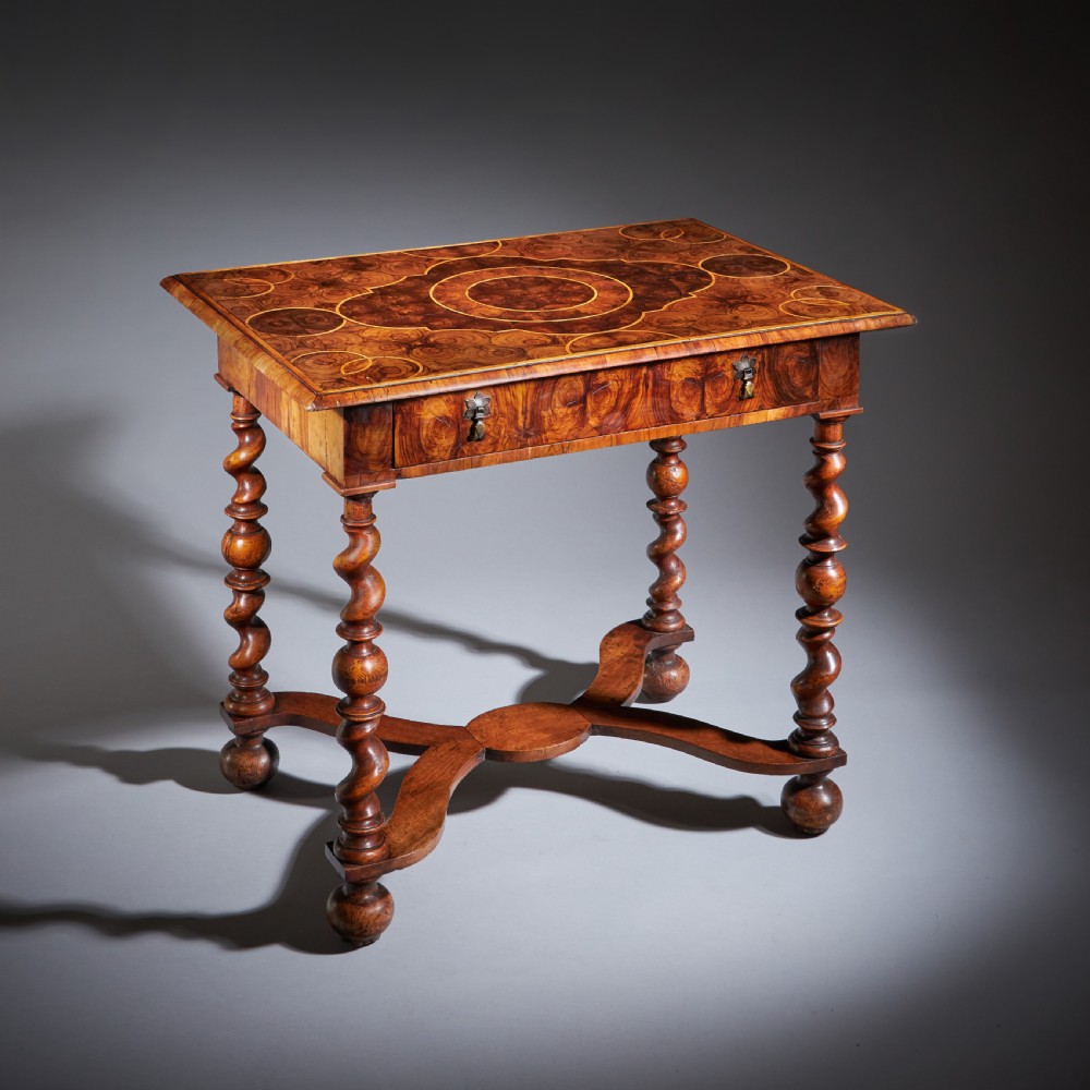 A late 17th-century William and Mary side table featuring intricate olive wood oyster veneering, barley-twist legs, an X-frame stretcher, and a frieze drawer.