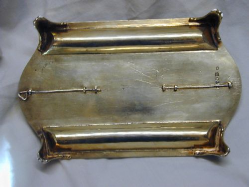 fig 2. A rectangular sterling silver partners inkstand featuring two raised circular inkwells with pierced lids, a central oval box, two pen troughs, and engraved crests.