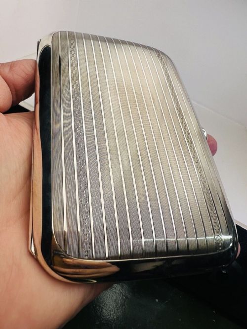 fig 1. A rectangular sterling silver cigarette case featuring engine-turned linear engraving and a push-button clasp.