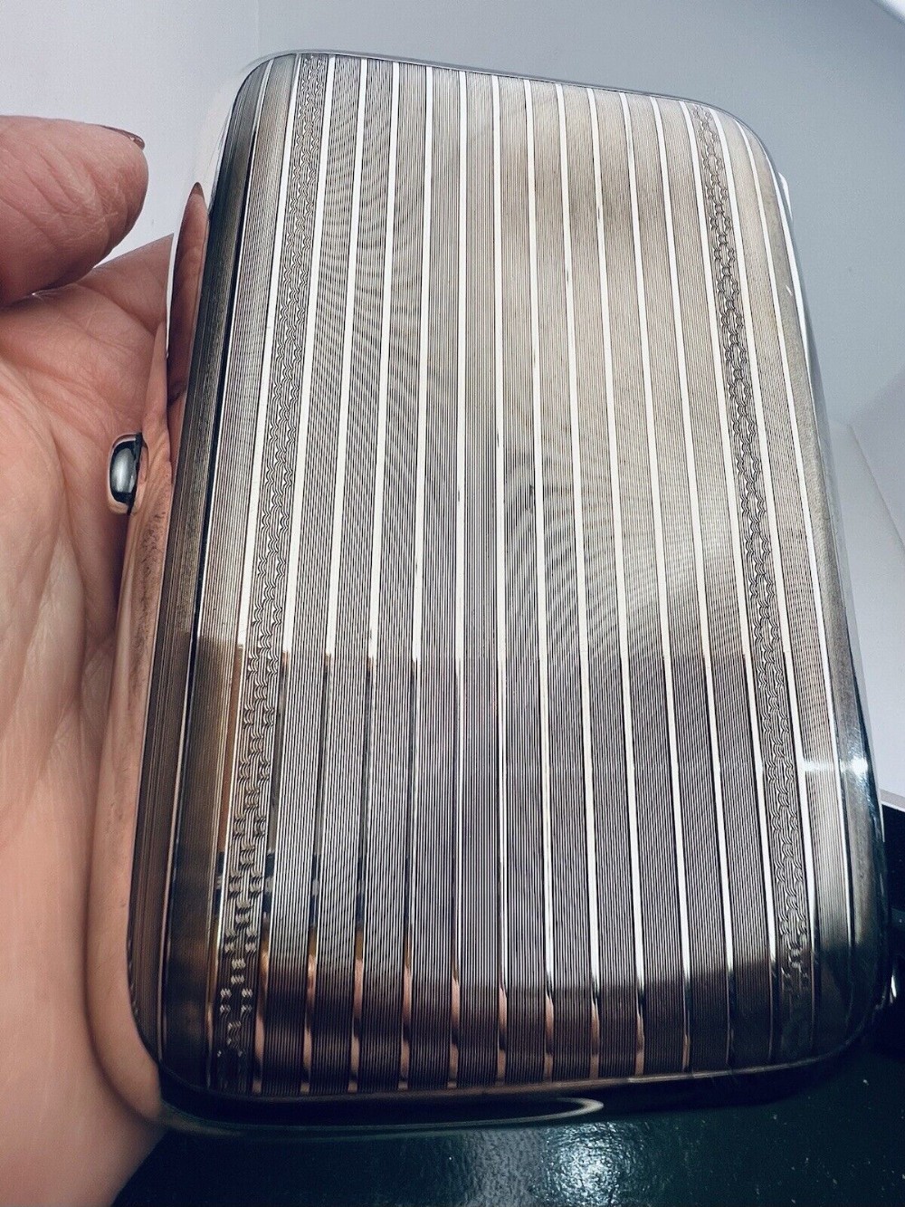 A rectangular sterling silver cigarette case featuring engine-turned linear engraving and a push-button clasp.