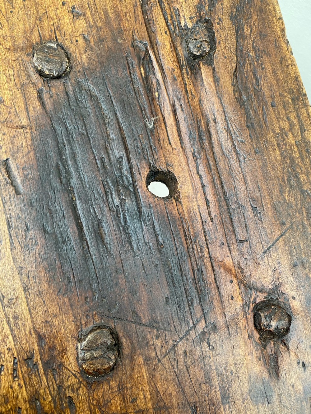 A small primitive wooden rushlight stool featuring four splayed legs wedged through a thick rectangular oak slab top. View III