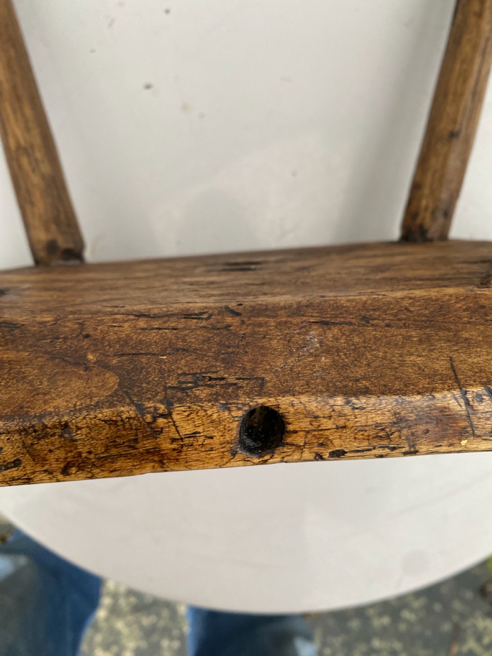 A small primitive wooden rushlight stool featuring four splayed legs wedged through a thick rectangular oak slab top. View VI