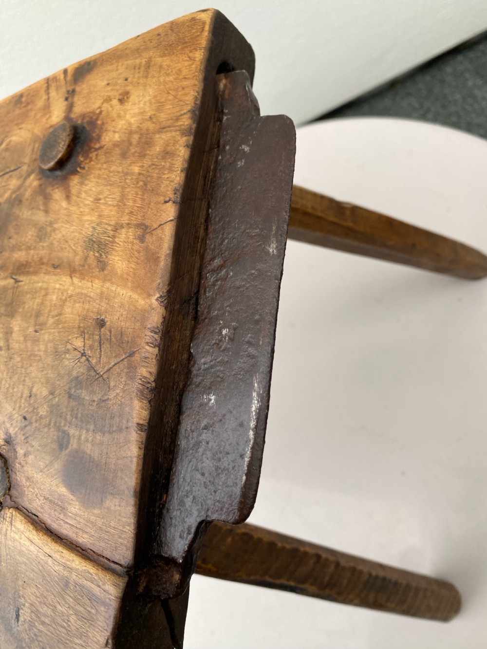 A rustic hand-carved rectangular wooden stool with four tapered legs wedged through a thick solid timber seat. View IV